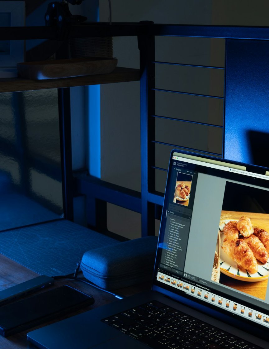 A laptop on a desk in a dim studio, showing a storefront design in progress